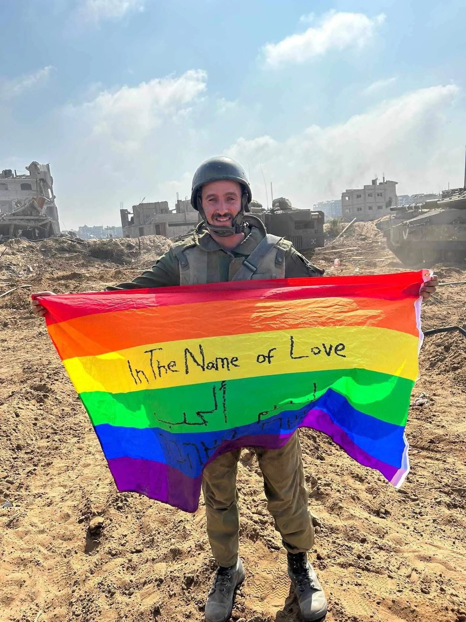 Pic. 1: Israeli soldier Yoav Atzmoni waving a rainbow flag with the words "In The Name of Love" in Gaza. Posted by the @Israel official account on X (Twitter).
